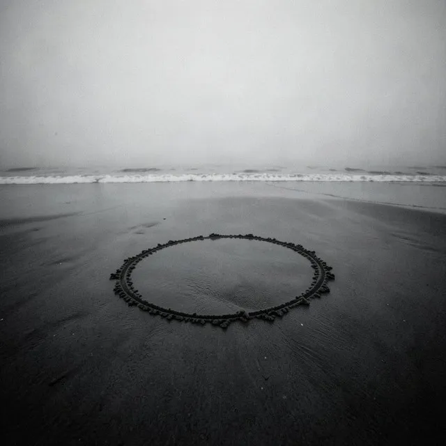 Circle in the Sand cover art: a ring of stones laid on wet sand at the water's edge, in black and white
