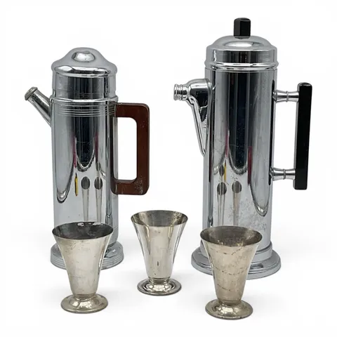 A pair of Art Deco chrome cocktail shakers with silver-plated cordial cups